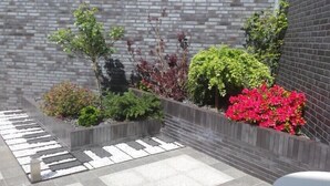 Un área de jardín ajardinada con diversas plantas y un muro de ladrillo.