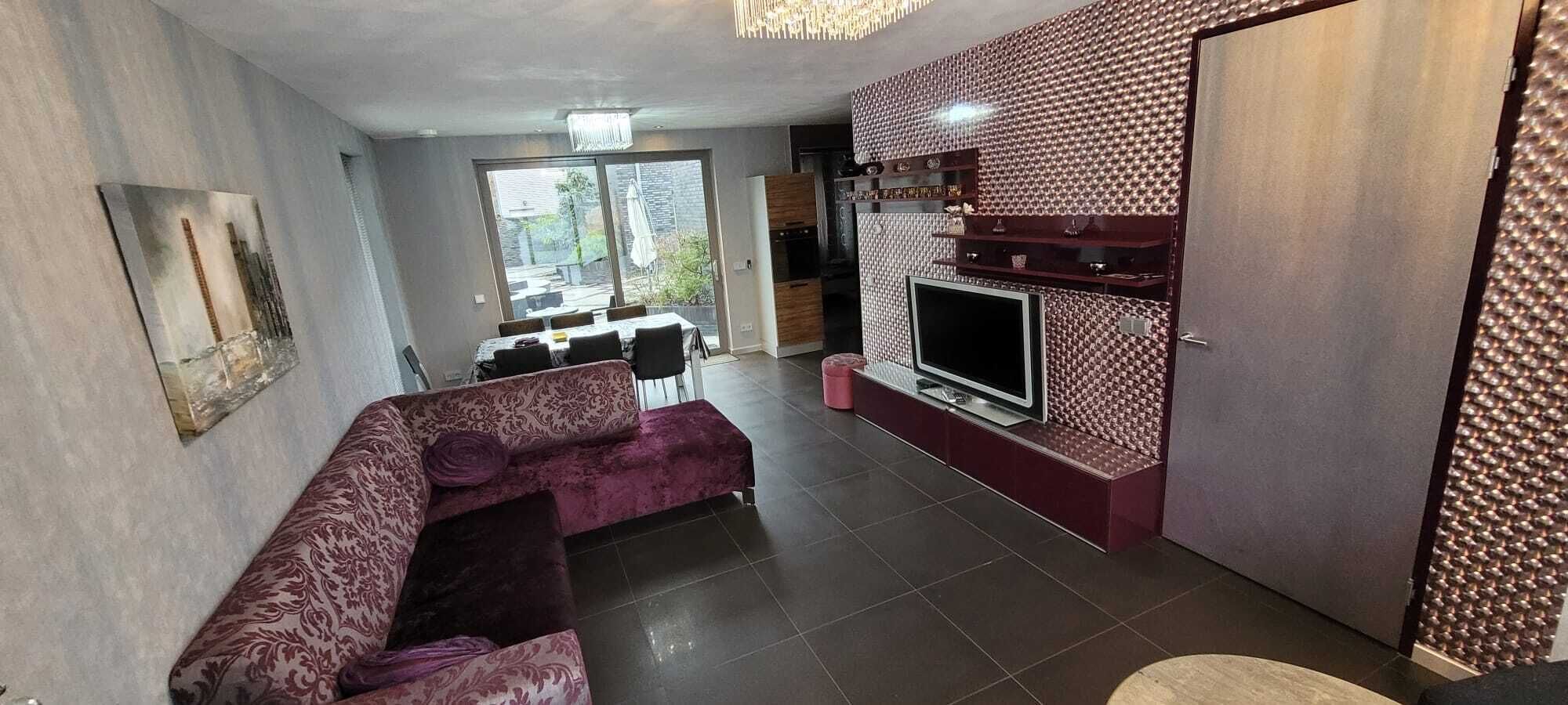 A modern living room with a sofa, a flat-screen TV, and a fireplace.
