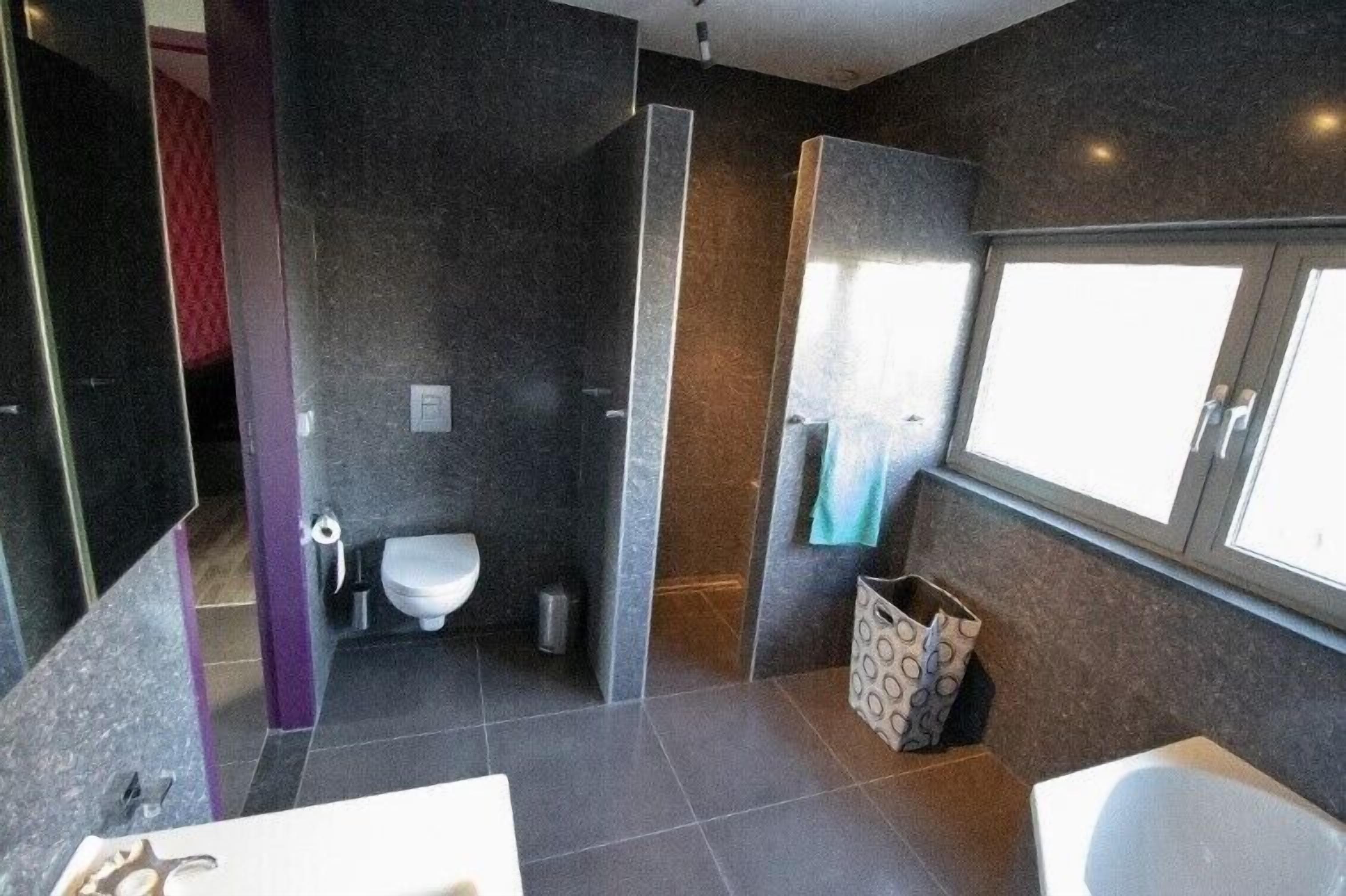 A modern bathroom with a toilet, bidet, and shower area.