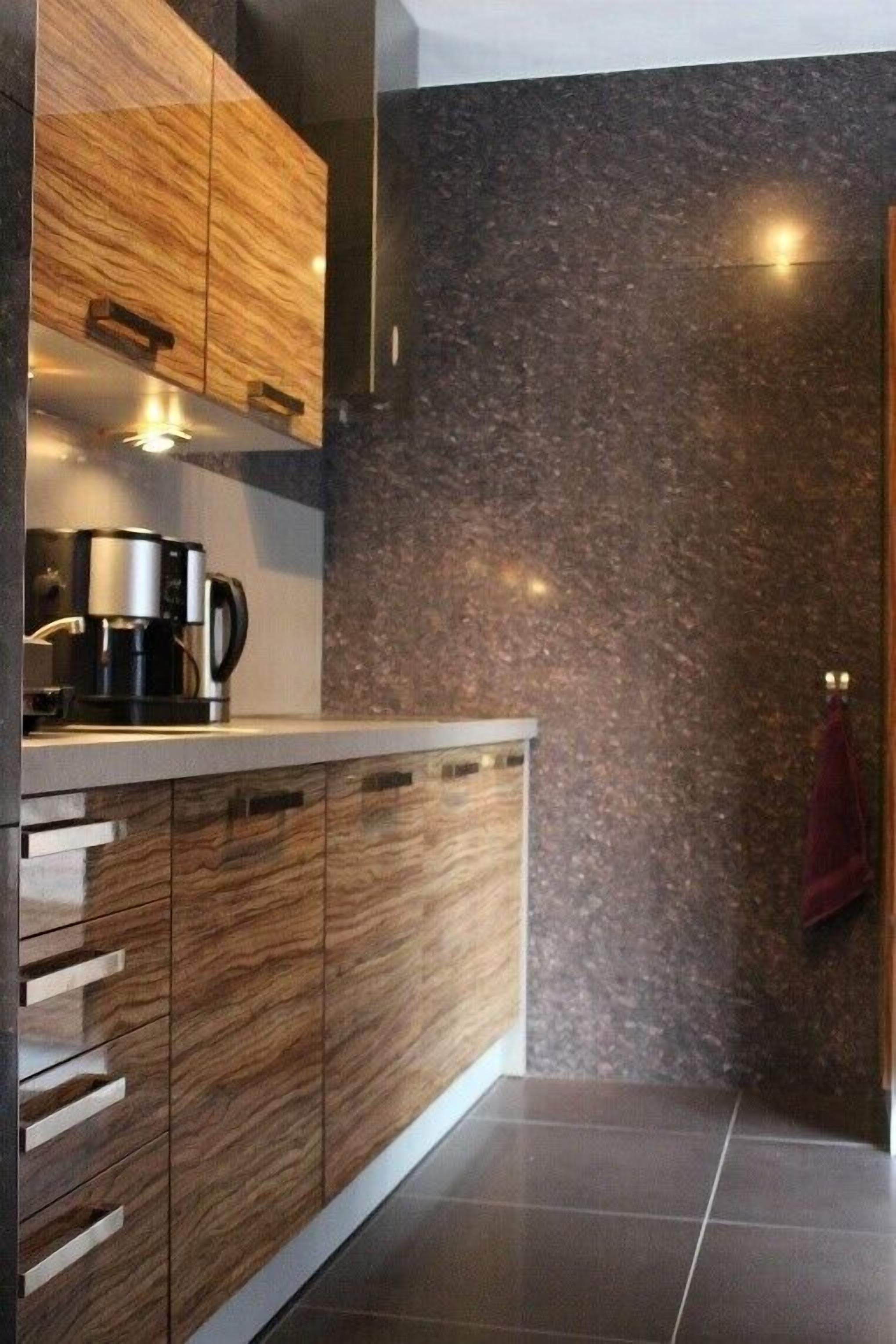 Une cuisine moderne avec des meubles en bois, une machine à café et un pare-feu en marbre.