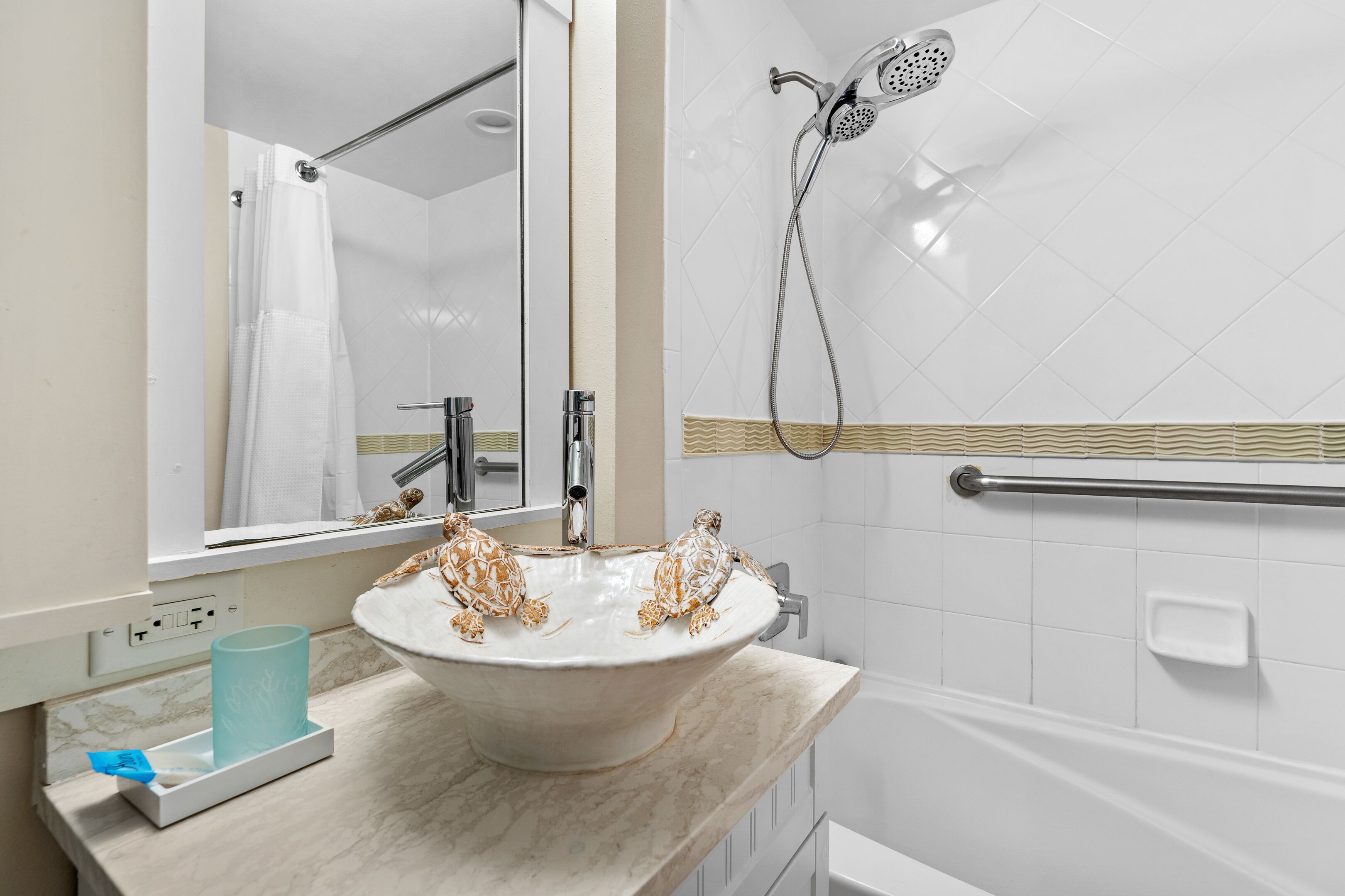 Une salle de bain avec un lavabo blanc, un miroir, une douche et un porte-serviettes.