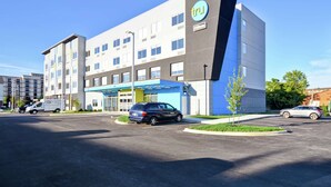 A modern hotel with a prominent 'tru' sign, a covered entrance, and a parking lot with several cars. - Tru by Hilton Louisville Airport (Louisville)