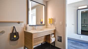 Un baño moderno con tocador de madera, un espejo grande y un perchero para toallas.