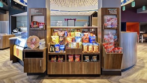 A snack display with various chips and snacks, a sign for 'eat & sip', and a 'check out our local items' sign. - Tru by Hilton Louisville Airport (Louisville)