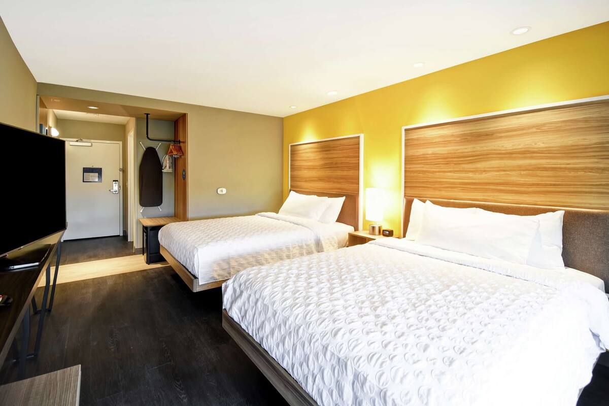 Une chambre d’hôtel avec deux lits, une télévision, une armoire et un miroir.
