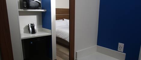 Habitación de hotel pequeña con microondas, cafetera y lavamanos.