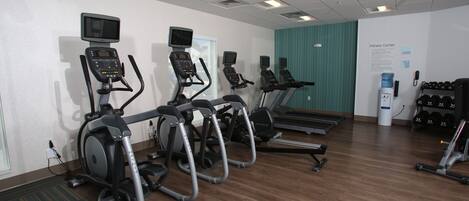 A fitness center with treadmills, ellipticals, and a wall-mounted screen.