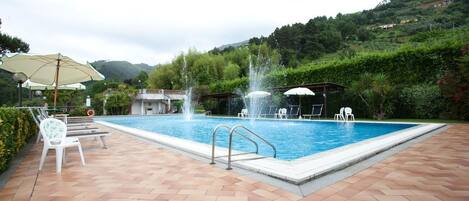 Alberca al aire libre, sombrillas en la alberca y camastros