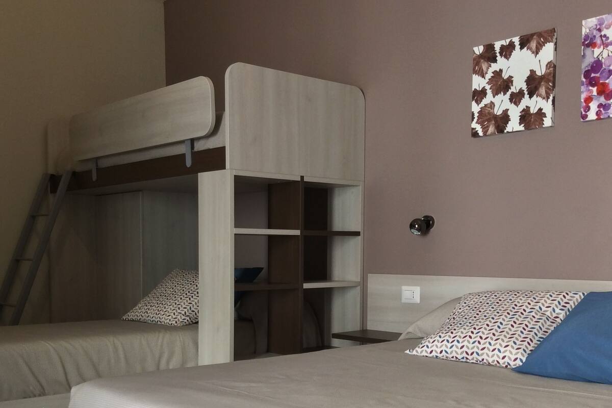 A bedroom with bunk beds, a ladder, and two wall art pieces.