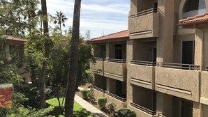 Un edificio de varios pisos con balcones, rodeado de exuberante vegetación y palmeras.