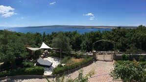 Un patio con toldo blanco, suelo de piedra y vista al mar.