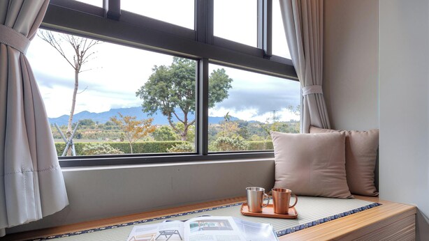 A room with a large window, a wooden bench with cushions, and a tray with two metal cups. - Beluck (Luye)