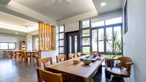 A spacious dining area with a long wooden table, multiple chairs, and large windows providing natural light. - Beluck (Luye)