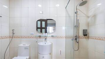 A bathroom with a toilet, sink, mirror, shower, and a towel rack.