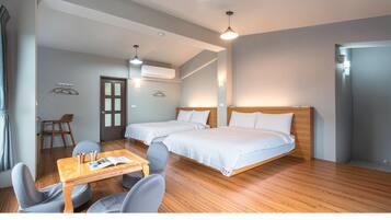 Une chambre avec deux lits, une table en bois avec des chaises, une porte et un appareil de climatisation.
