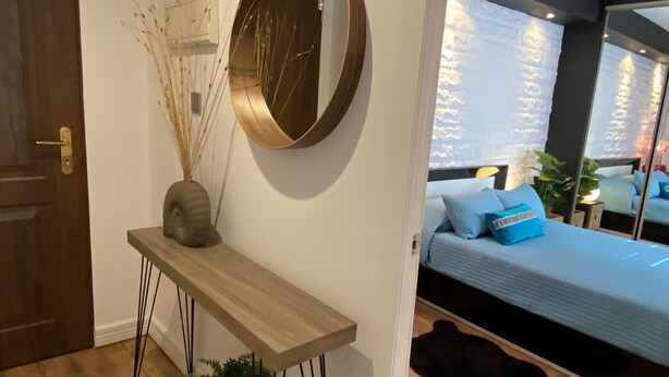 Un dormitorio moderno con cama, mesita de noche, espejo y planta en maceta.