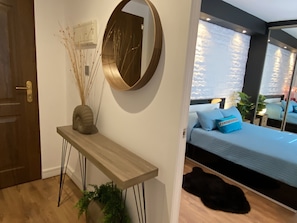 Een moderne slaapkamer met een bed, nachtkastje, spiegel en een potplant.