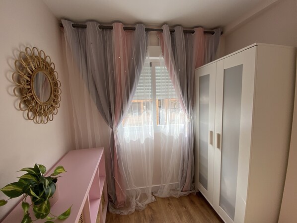A room with a large wardrobe, a mirror, sheer curtains, a pink console table, and a potted plant. - COMFORTABLE APARTMENT WITH WIFI, BETWEEN CITY OF ARTS AND BEACHES (València)