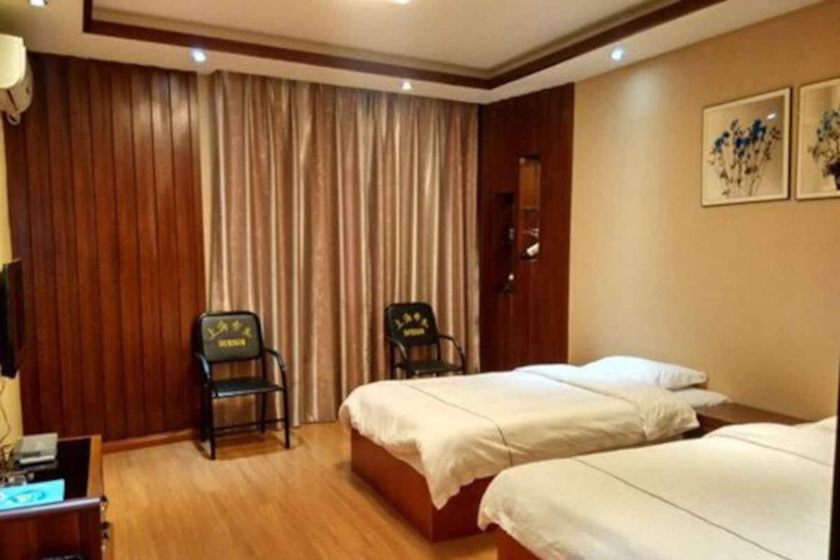 Habitación de hotel con dos camas, paneles de madera, un escritorio con lámpara y una silla.