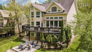 A two-story house with a deck, outdoor seating, and a fire pit. - Luxury Lakefront w/ Hot Tub & Rec Room (Oakland)