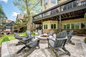 Um pátio com cadeiras Adirondack, uma lareira e um deck coberto.