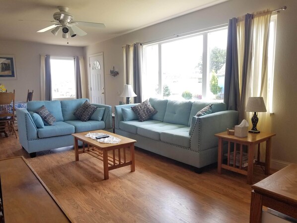 A living room with two light blue sofas, a wooden coffee table, and a side table with a lamp.