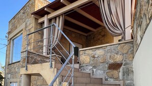 Un edifici de pedra amb una escala que condueix a una terrassa de fusta.