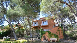 A two-story building with a stone facade, a balcony, and a statue in the garden. - Holiday rental villa with swimming pool in Begur, Sa Tuna (Begur)