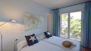 A hotel room with two beds, a large window with curtains, a lamp, and a wall painting. - Holiday rental villa with swimming pool in Begur, Sa Tuna (Begur)