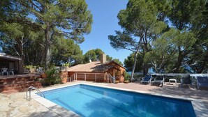 A swimming pool with a tiled deck, surrounded by trees and a wooden building with a tiled roof. - Holiday rental villa with swimming pool in Begur, Sa Tuna (Begur)