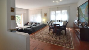 A living room with a sofa, a dining table with chairs, a rug, and a painting on the wall. - Holiday rental villa with swimming pool in Begur, Sa Tuna (Begur)