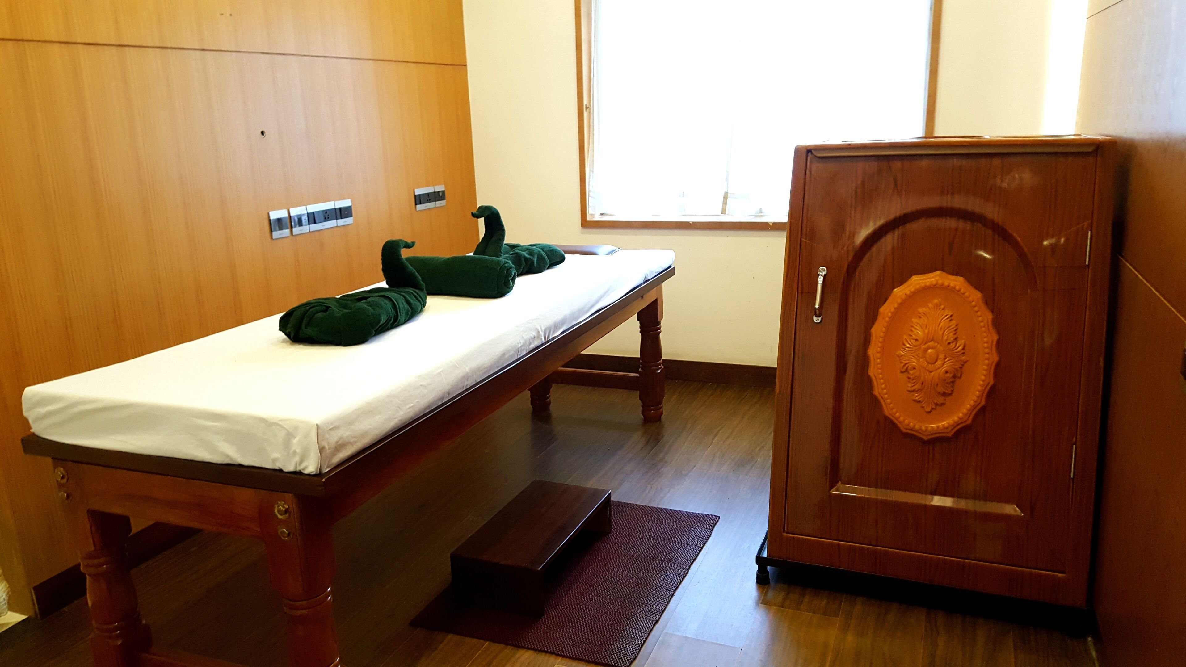 A room with a wooden bed, a bench, a cabinet, and a window.