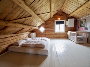A cozy attic bedroom with a wooden ceiling, a single bed, a crib, and a window with a view. - Lighthouse View Lofoten (Vestvågøy)