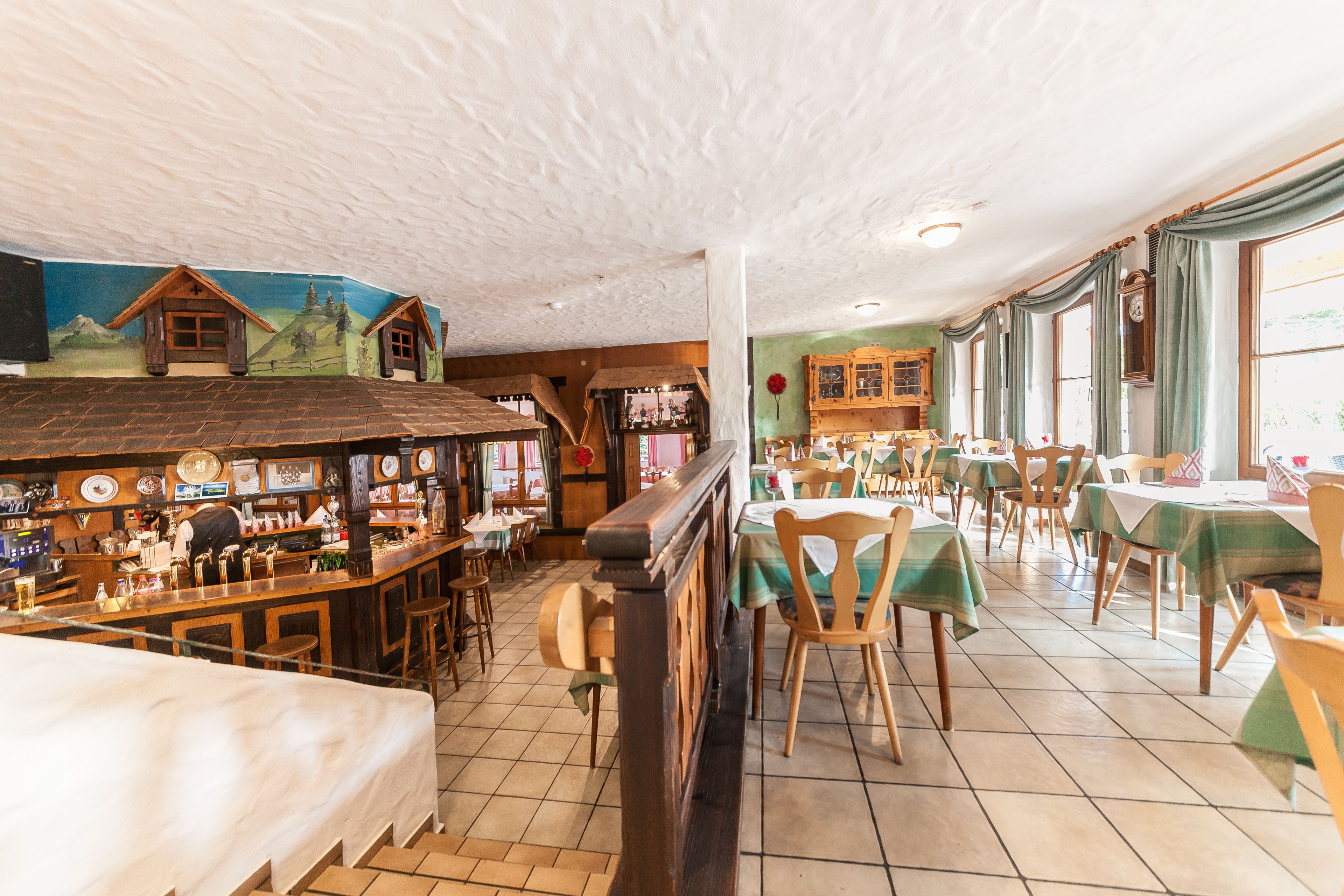 A cozy restaurant with wooden furniture, a bar area, and a mural on the wall.