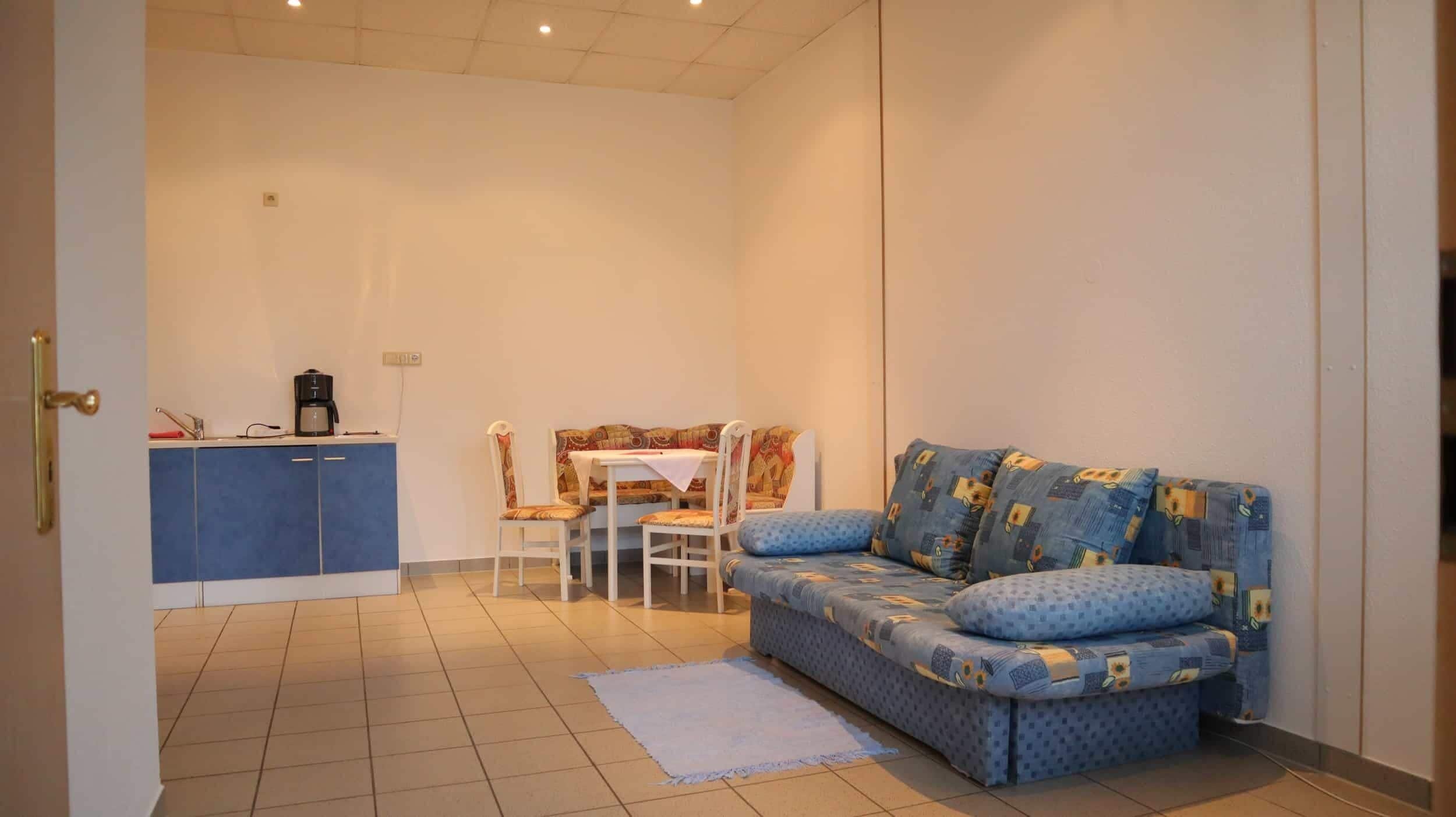 A small living room with a sofa, a coffee table, and a dining area with a table and chairs.