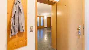 A hallway with a wooden door, a coat rack, and a tiled floor. - Toni's Tenne (Eschbach)