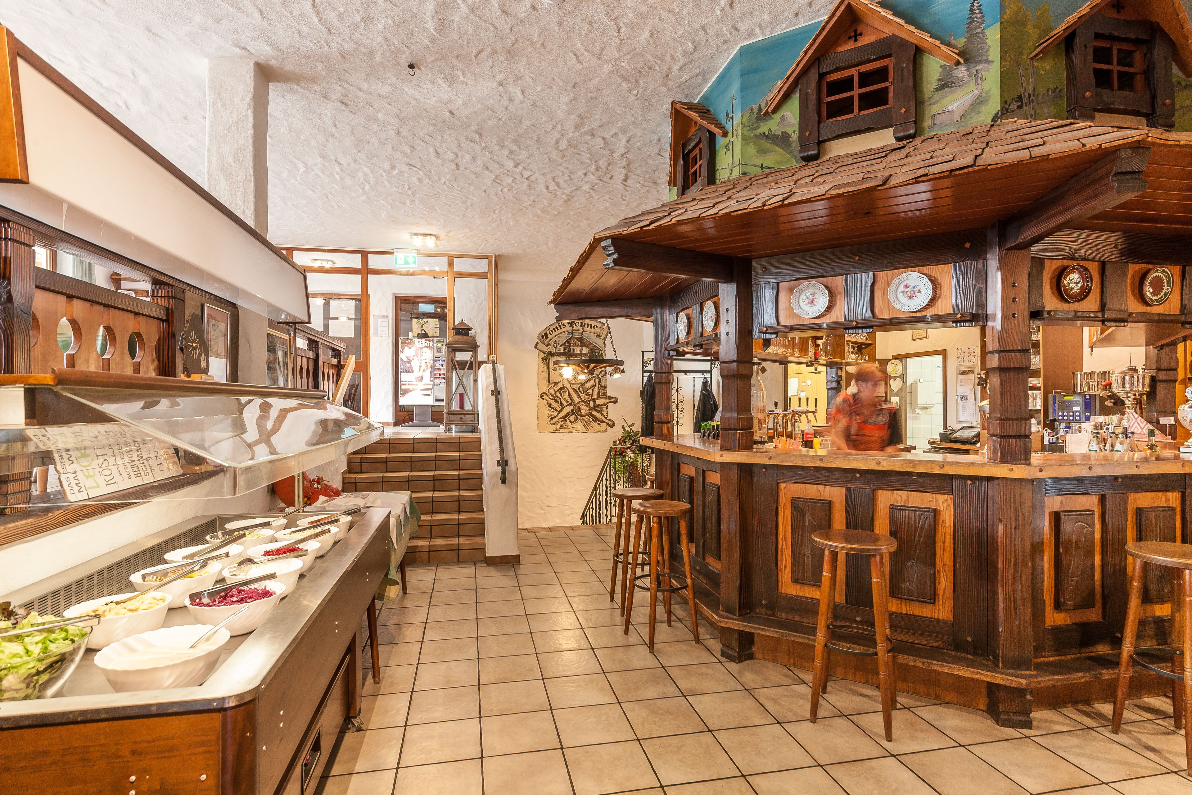 Un espace buffet proposant une variété de plats et un bar équipé de tabourets et d’un comptoir.