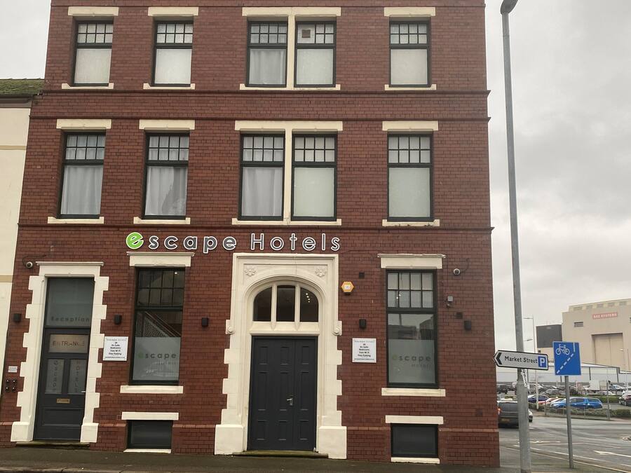 A two-story brick building with a sign reading "Escape Hotels".