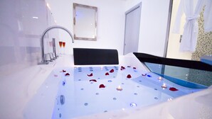 A modern bathroom with a bathtub, a mirror, and a shower area. - Love Loft (Bordeaux)