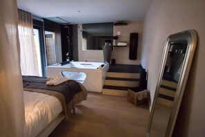 A hotel room with a bed, a bathroom with a bathtub, a mirror, and a staircase. - Love Loft (Bordeaux)