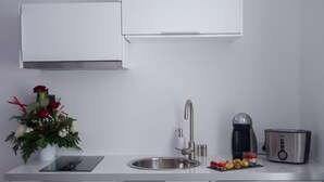 A modern kitchen with white cabinets, a stainless steel sink, a coffee maker, and a toaster. - Love Loft (Bordeaux)
