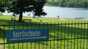 A sign for a 'Surfschule' (surf school) with an arrow pointing to the right, indicating the direction to the surf school. - House Luise on Bostalsee, apartment 1: panoramic view and large balcony (Saar)