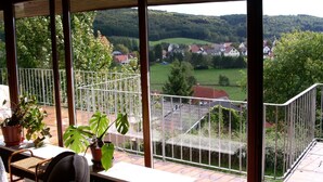 A balcony with a view of a rural landscape, including houses and greenery. - House Luise on Bostalsee, apartment 1: panoramic view and large balcony (Saar)