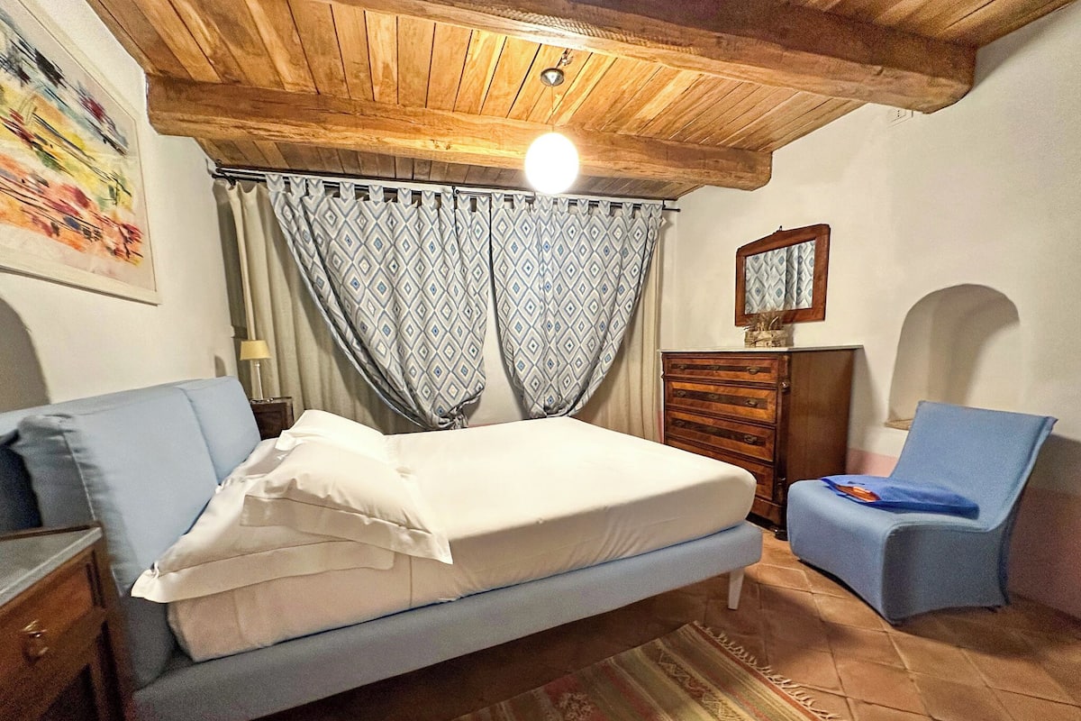 A bedroom with a bed, a chair, a dresser, and a ceiling light.