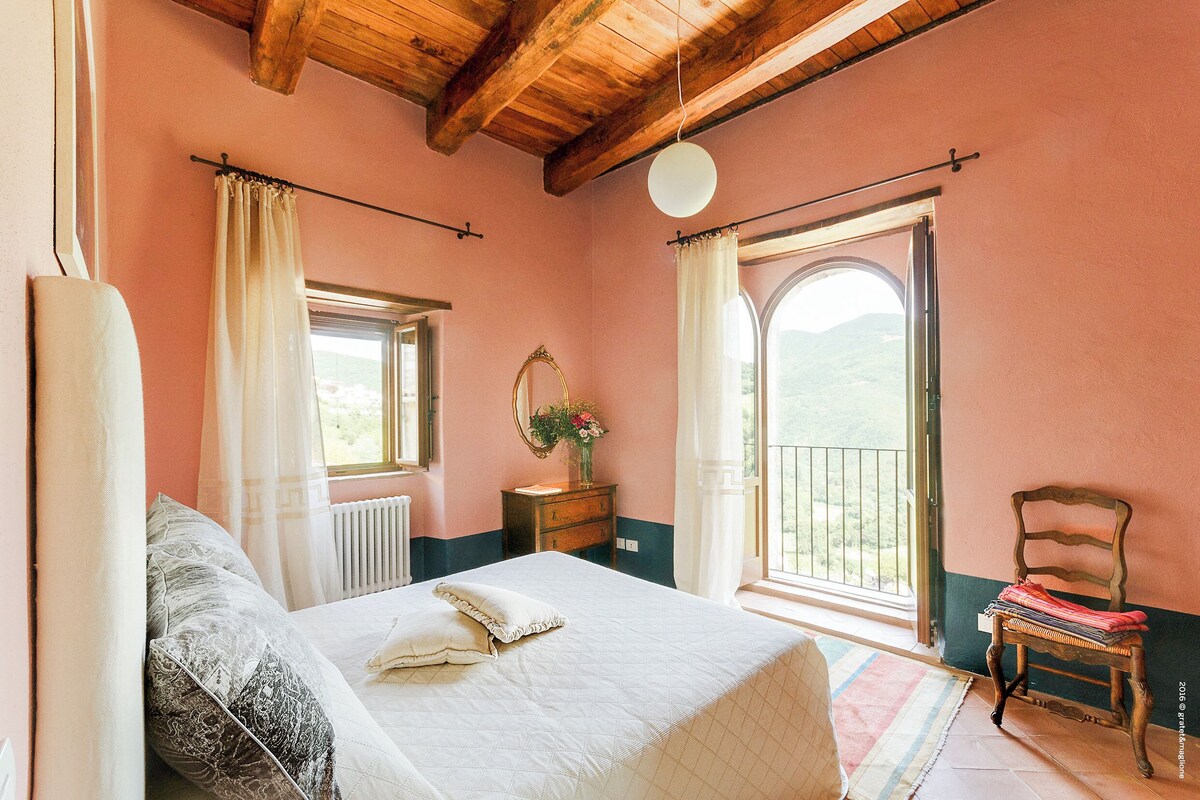 A bedroom with a bed, a dresser, a chair, a window, and a balcony.