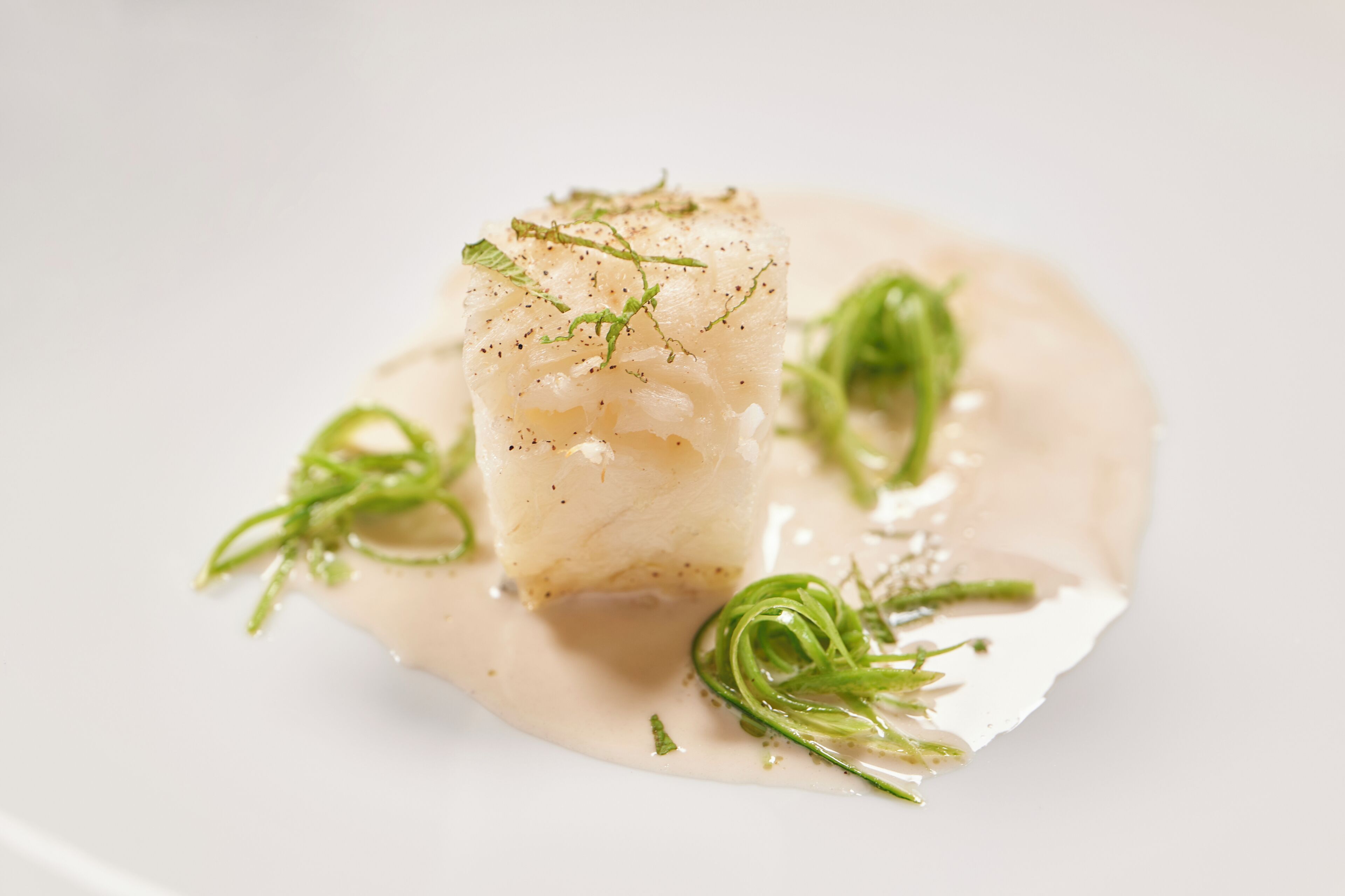 A dish with a creamy sauce and green garnish.