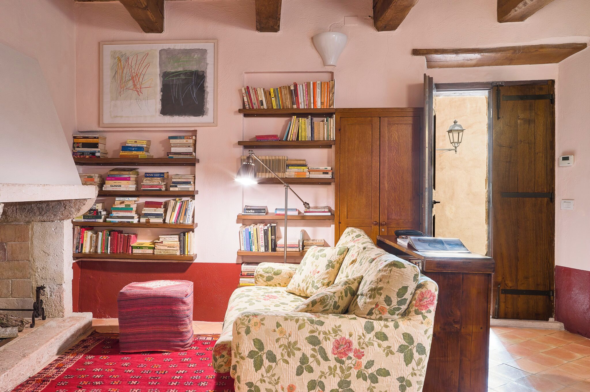 Een gezellige woonkamer met een open haard, een boekenkast, een bloemenbank en een houten deur.