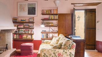 Een gezellige woonkamer met een open haard, een boekenkast, een bloemenbank en een houten deur.