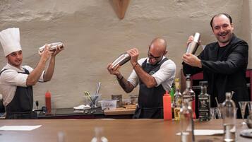 Un bar avec des barmen préparant des boissons, un comptoir où sont exposées différentes bouteilles et un mur à motifs.