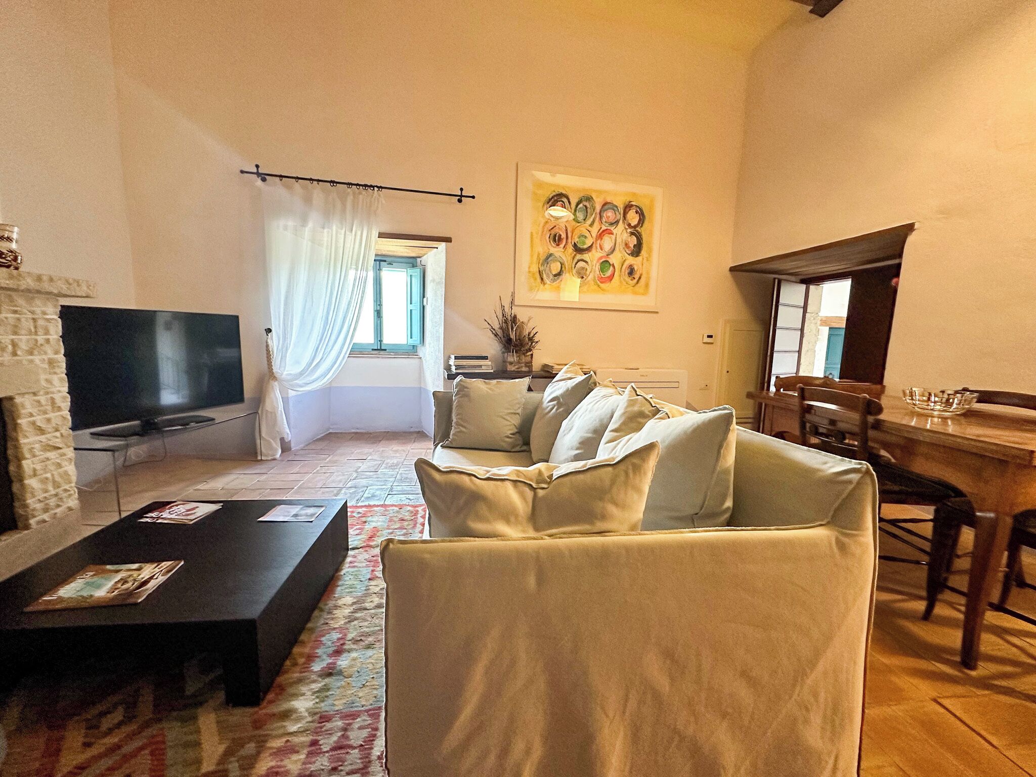 A living room with a TV, sofa, and a dining area with a table and chairs.